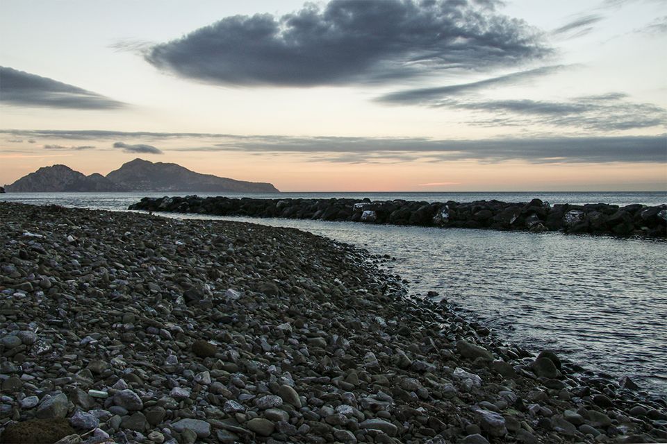 The pebble beach at San Montano at sunset, with Capri on the horizon.